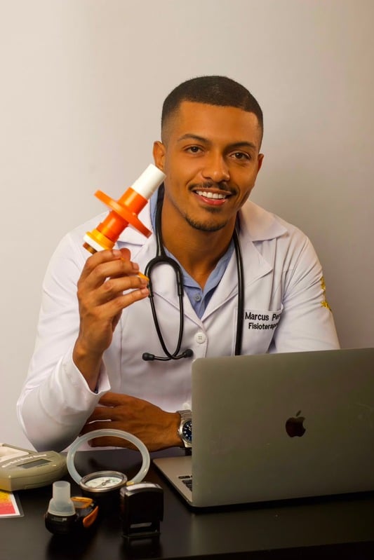Marcus Pereira segurando um incentivador respiratório ao lado de um notebook